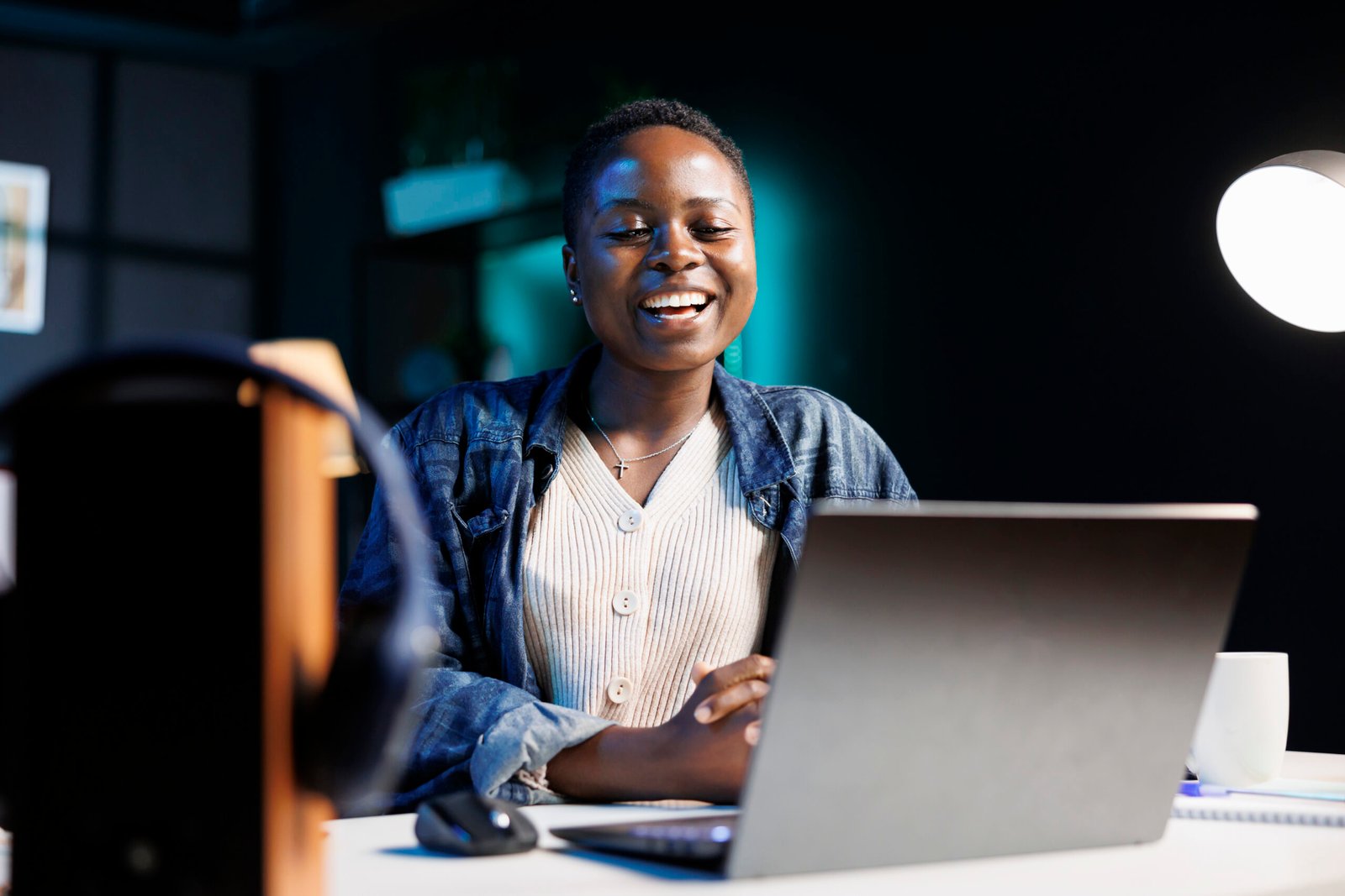 Black woman enjoying a comedy movie on her digital laptop, while seated at desk in her apartment. Excited african american lady using personal computer for virtual online communication with friends.